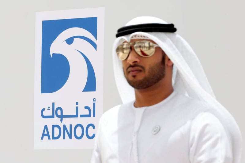 FILE PHOTO: An Emirati man is seen near the logo of  ADNOC in Ruwais, United Arab Emirates May 14, 2018. REUTERS/Christopher Pike/File Photo