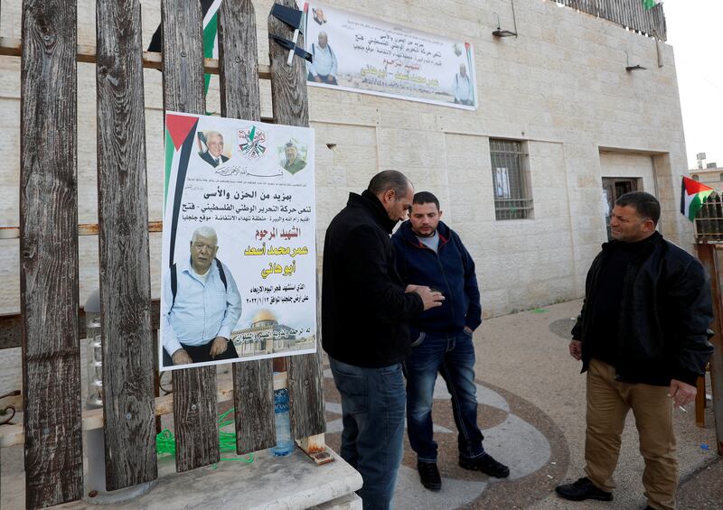Men stand next to a poster of Palestinian-American Omar Abdalmajeed Asad, 80, in the village of Jiljilya in the Israeli-occupied West Bank on January 12.  Reuters