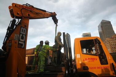 Workers transport a statue of slave owner Robert Milligan which was taken down, in West India Quay, east London, Tuesday, June 9, 2020, after a protest saw anti-racism campaigners tear down a statue of a slave trader in Bristol. PA via AP