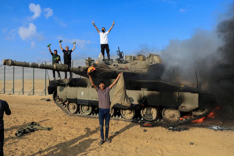 Palestinians celebrate as an Israeli tank burns after it was hit by Palestinian gunmen in southern Israel. Reuters