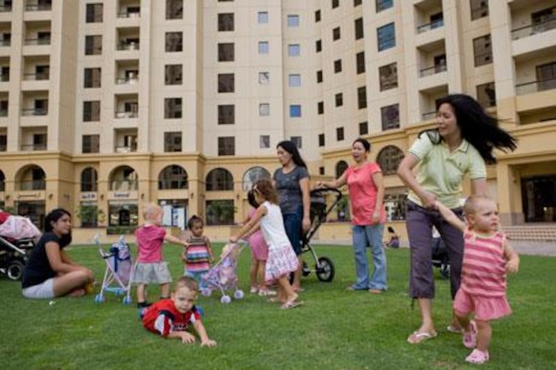 Nannies relax with their employers' children on a lawn outside Jumeirah Beach Residences in Dubai .