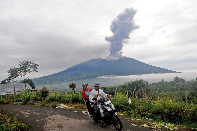 Motorists ride past by as Mount Marapi spews volcanic materials during its eruption in Agam, West Sumatra, Indonesia, Monday, Dec.  4, 2023.  The volcano spewed thick columns of ash as high as 3,000 meters (9,800 feet) into the sky in a sudden eruption Sunday and hot ash clouds spread several miles (kilometers).  (AP Photo / Ardhy Fernando)