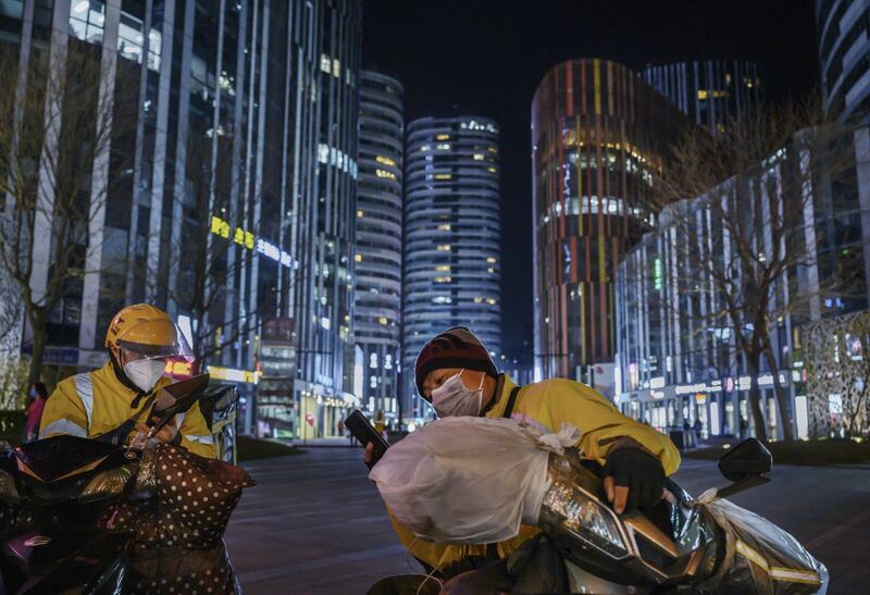 Chinese courier drivers wear protective masks as they wait for calls in a shopping area in Beijing. Getty Images