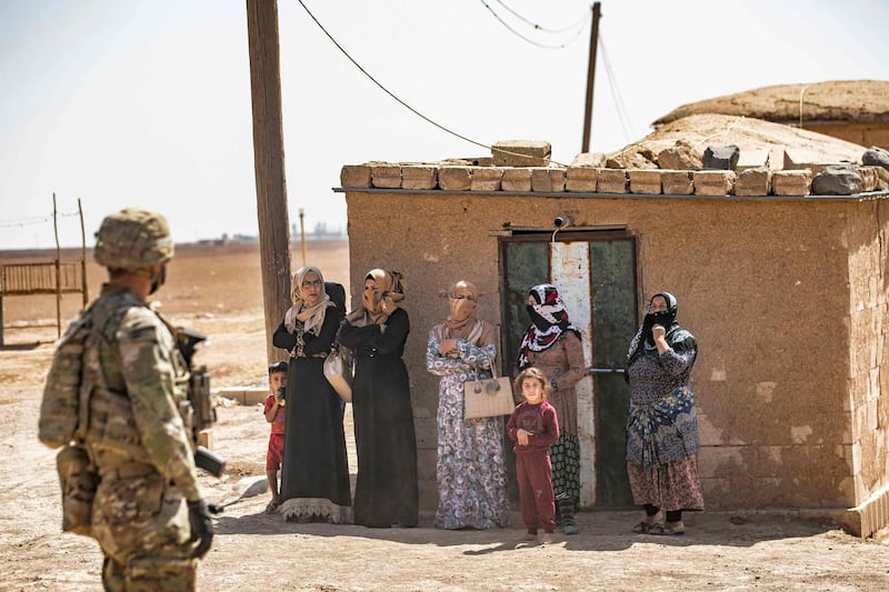 A US soldier looks on as local women and children stand by during a military patrol in Rmelan. AFP