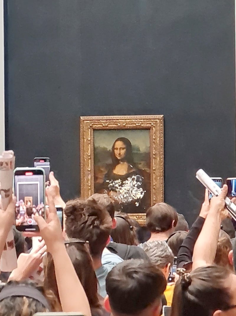 Visitors take pictures and video of the 'Mona Lisa' after cake was smeared on its protective glass at the Louvre Museum in Paris on May 29. Photo: Twitter / @klevisl007 via Reuters