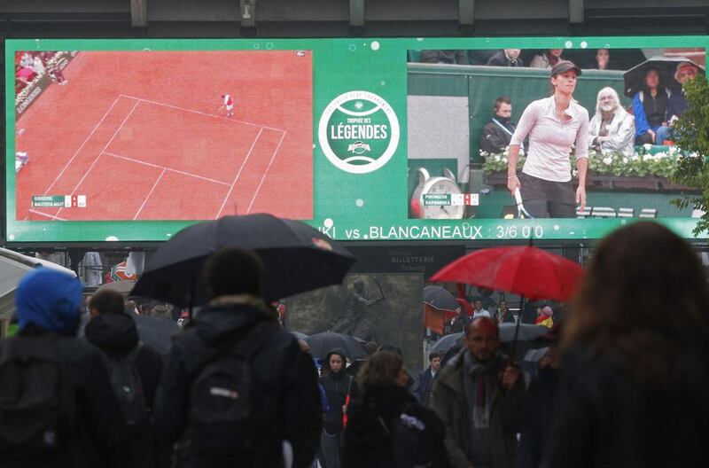 Spectators holding umbrellas walk towards Suzanne Lenglen stadium. Christophe Ena / AP Photo