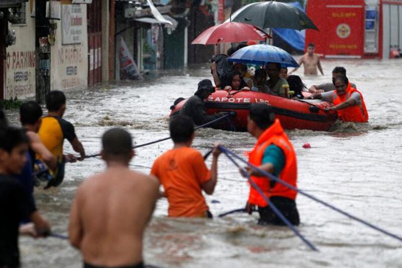 epa03830384 Filipino rescuers pull a rubber boat along a flooded street in Las Pinas City, south of Manila, Philippines, 19 August 2013. The Philippines weather bureau continues to track tropical storm Trami which has been estimated at 550 kilometers east of Batanes province in the northern Philippines with maximum winds of 75 kilometers per hour. Metro Manila experienced flashfloods from heavy rains due to a southwest monsoon being enhanced by Trami local media reports stated.  EPA/FRANCIS R. MALASIG