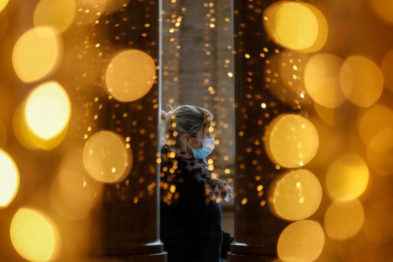 A woman wearing a protective mask is seen passing by Christmas decorations in Rome, Italy. Reuters