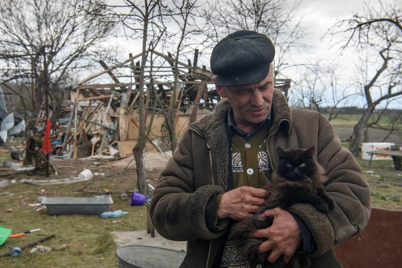 A local resident Serhii pets a cat next to a residential house destroyed by a military strike during Russia's invasion in the village of Kukhari, in Kyiv region, Ukraine. Reuters