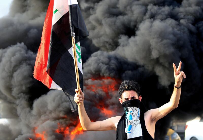 A demonstrator gestures as he stands close to burning tyres in Baghdad. Reuters