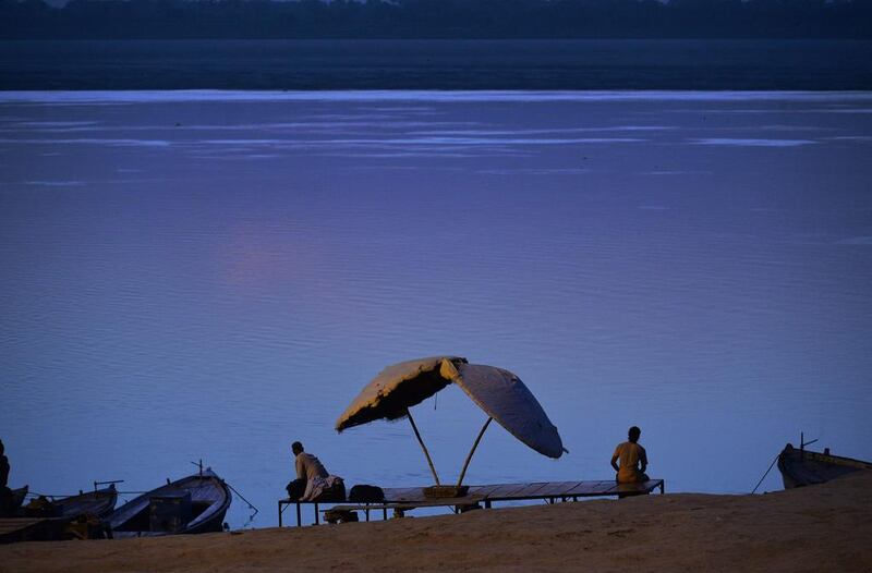 Two Indian men sit on the banks of the river Ganges at day break near one of the Ghats of Varanasi, India. Roberto Schimdt / AFP  