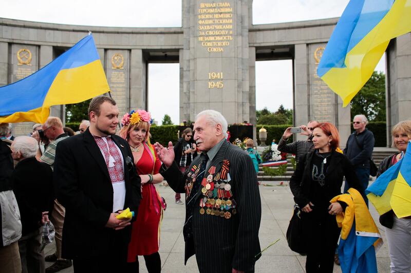 FILE  - In this Friday, May 8, 2015 file photo, Soviet war veteran David Dushman, 92, center, speaks to people holding Ukrainian flags as he attends a wreath laying ceremony at the Russian War Memorial in the Tiergarten district of Berlin, Germany. Dushman, the last surviving Allied soldier involved in the liberation of Auschwitz, has died. The Jewish Community of Munich and Upper Bavaria said Sunday, June 6, 2021 that Dushman had died a day earlier in a Munich hospital at the age of 98. As young Red Army soldier, Dushman flattened the forbidding fence around the notorious Nazi death camp with his tank on Jan. 27, 1945. (AP Photo/Markus Schreiber, File)
