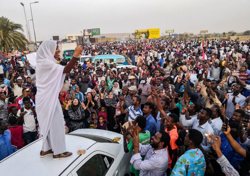 Alaa Salah, a Sudanese woman propelled to internet fame earlier this week after clips went viral of her leading powerful protest chants against President Omar al-Bashir, addresses protesters during a demonstration in front of the military headquarters in the capital Khartoum on April 10, 2019. - In the clips and photos, the elegant Salah stands atop a car wearing a long white headscarf and skirt as she sings and works the crowd, her golden full-moon earings reflecting light from the fading sunset and a sea of camera phones surrounding her. Dubbed online as "Kandaka", or Nubian queen, she has become a symbol of the protests which she says have traditionally had a female backbone in Sudan. (Photo by - / AFP)