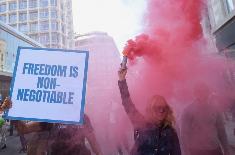 A woman releases coloured smoke, as she takes part in an anti-lockdown 'Unite for Freedom' protest in London. Reuters