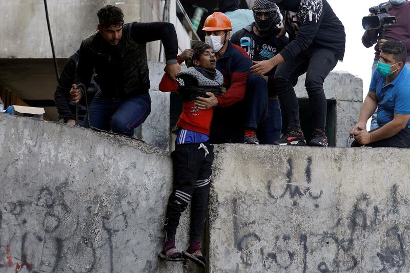 Demonstrators help a wounded young man after being hit by a stone during the ongoing anti-government protests in Baghdad. REUTERS