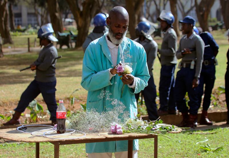 A florist is seen at work as armed riot police patrol a park. AP Photo