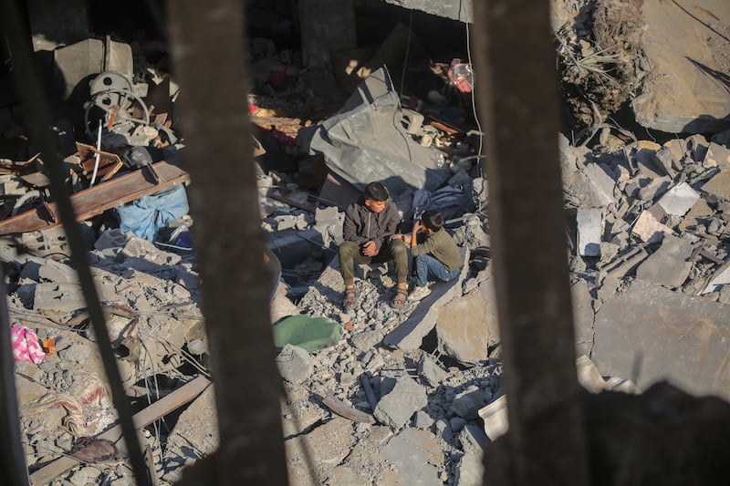 People sit amid the rubble of their homes following Israeli air strikes. Getty Images