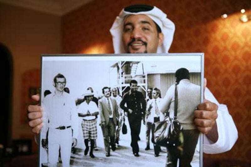 Ali Kaddas al Rumaithi holds a 1969 photograph of Muhammad Ali touring his father's greenhouses on Saadiyat Island during the boxer's visit to Abu Dhabi. Among those accompanying Ali is Mr al Rumaithi's father, Abdullah Kaddas al Rumaithi, in checkered shorts and white hat.