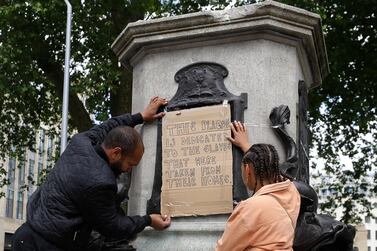 A banner is taped over the inscription on the pedestal of the toppled statue of Edward Colston in Bristol, England AP