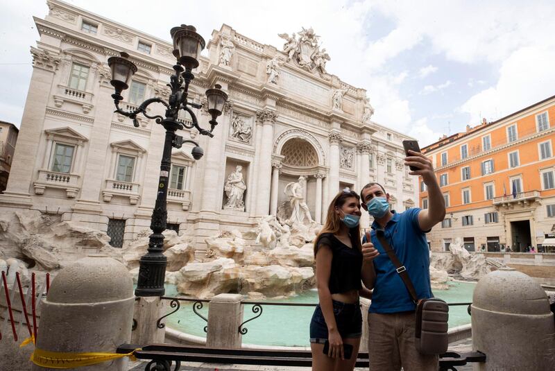 epa08430474 Tourists take a selfie in front of Trevi Fountain during phase 2 of the COVID-19 coronavirus emergency in Rome, Italy, 18 May 2020. Several countries around the world have started to ease COVID-19 lock-down restrictions in an effort to restart their economies and help people in their daily routines after the outbreak of coronavirus pandemic.  EPA/MASSIMO PERCOSSI