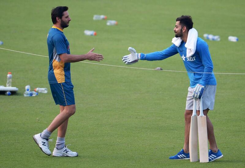 Pakistan’s Shahid Afridi, left, and Virat Kohli of India engage in pre-match friendly gestures before their rivalry resumes on Saturday. Dibyangshu Sarkar / AFP