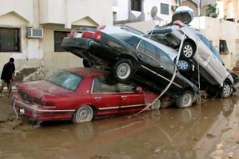 A man cleans outside a house next to a pile of cars in Jeddah in November, 2009 following a flash flood. 120 people died in the flood and tens of thousands were displaced.
