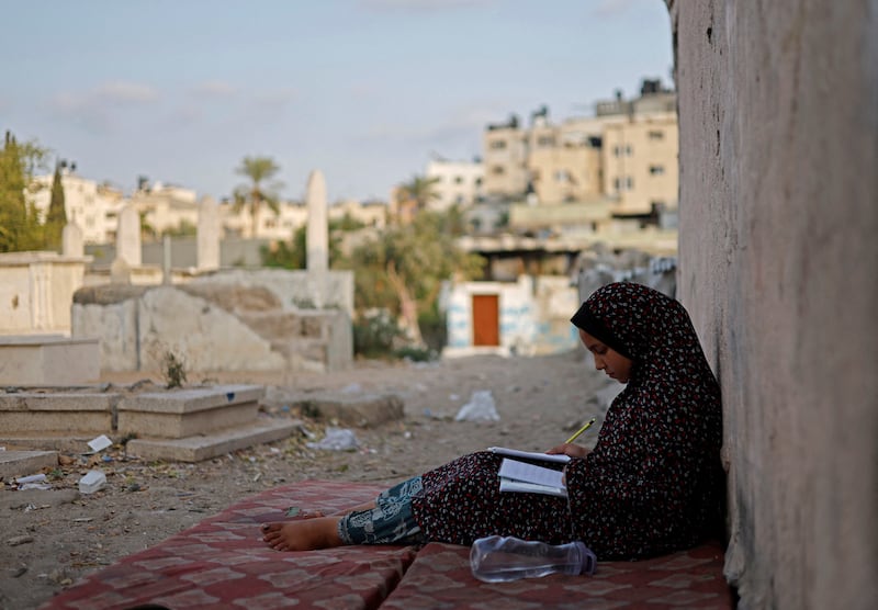 Lamis Kuhail studies for school in Sheikh Shaban cemetery. 'I sometimes get invited by friends from school, but I can't invite them here,' she said.