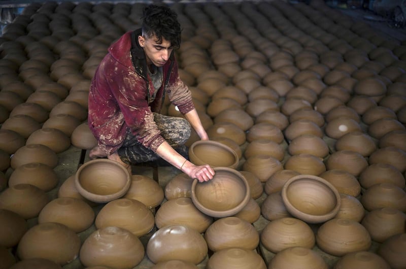 A son of Palestinian potter Sid Atallah lays out clay bowls to dry at the family workshop in Deir al-Balah in the central Gaza Strip. AFP