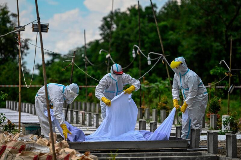 Volunteers wearing personal protective equipment suits bury the body of a person suspected of dying from the Covid-19 coronavirus at a cemetery, in Yangon.  AFP