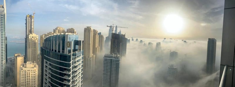 The sun rises behind skyscrapers amidst the clouds on a foggy morning in the Dubai Marina. Ollie Maher