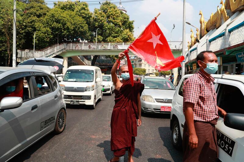 A Buddhist monk waves the flag of deposed Myanmar leader Aung San Suu Kyi's National League for Democracy party in the middle of a street in Yangon, Myanmar. AP