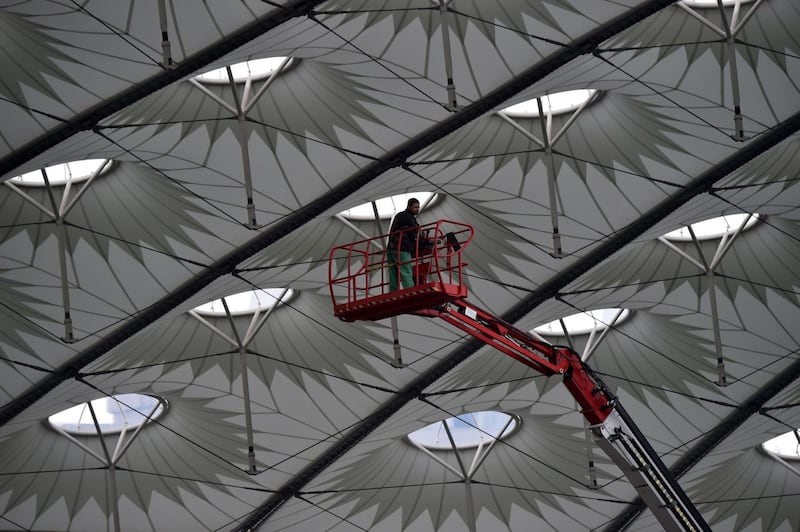 A worker stands on a hoist inside The NSC Olimpiyskiy Stadium in Kiev, on May 14, 2018, ahead of the 2018 UEFA Champions League Final football match between Liverpool and Real Madrid. Sergei Supinsky / AFP Photo