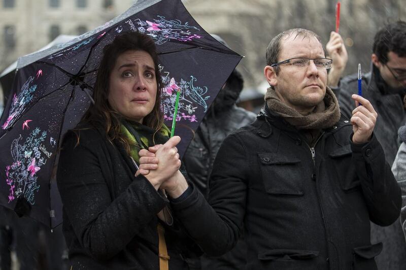 A woman, grasping a symbolic pencil,  is moved to tears as people gather in front of Notre Dame cathedral for a minute of silence in memory of the 12 victims in the January 7, 2015, massacre at the Paris headquarters of satirical magazine Charlie Hebdo. Ian Langsdon / EPA / January 8, 2015