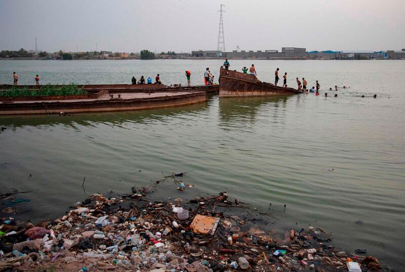 Iraqi youths play atop a sunken boat in front of amid rubbish floating in the Shatt Al Arab river in the southern port city of Basra.  AFP