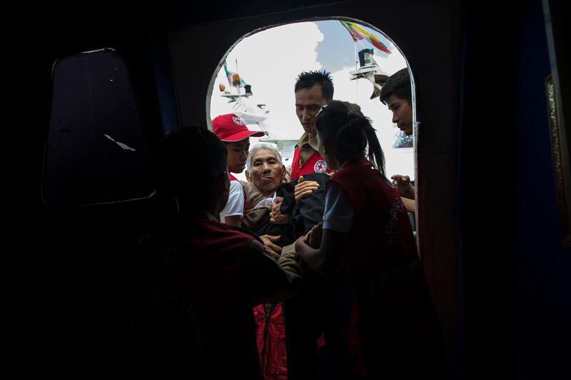 Members of Myanmar's Red Cross carry an elderly woman fleeing a conflict area in Rakhine State. At least 18,500 Rohingya have fled into Bangladesh in the last six days since renewed fighting broke out between militants and the  Myanmar army. Ye Aung Thu / AFP Photo