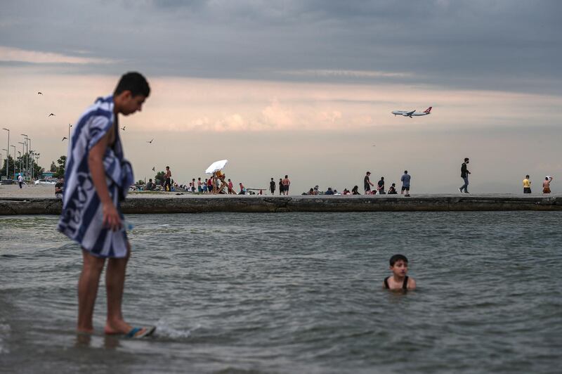 A Turkish Airlines plane prepares for landing as Syrian refugees enjoy their weekend at Menekse Beach, amid the ongoing pandemic in Istanbul, Turkey.  EPA