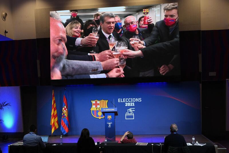 Journalists watch Spanish lawyer Joan Laporta (on screen) drinking a toast to celebrate his victory in the Barcelona presidential elections. AFP