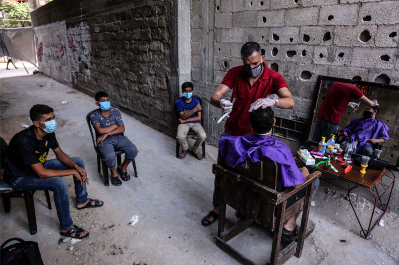When barber shops in Gaza closed due to the pandemic, Sameh decided to set up shop outdoors in his neighborhood. Here, he tends to the children of his relatives and neighbors, while everyone maintains social distancing protocols. Photo by Samar Abu Elouf