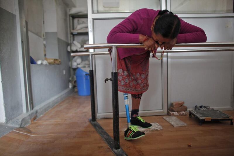 Daan Maya Maharjan, 47, who lost a leg in the April 25 earthquake, looks at her prosthetic while practicing to walk with it at a rehabilitation center in Kathmandu, Nepal. Niranjan Shrestha / AP Photo