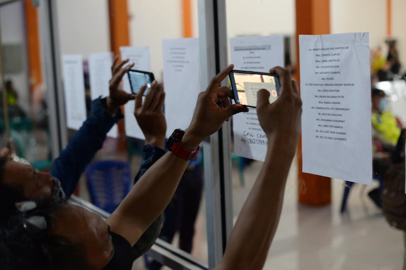 A number of family members of Sriwijaya Air SJ 182 passengers using mobile phones take pictures of their relatives' names from notes attached on the window of an office as they wait news on their loved ones, at Pontianak Supadio International Airport, in Pontianak, West Kalimantan, Indonesia.  EPA