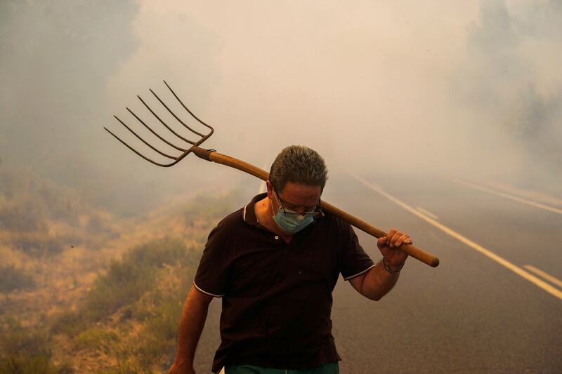 A volunteer helps to extinquish a wildfire in the village of Navalmoral, Spain.