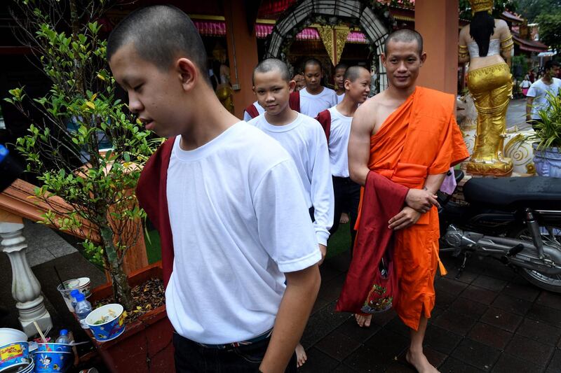 Coach Ekkapol Chantawong, right, and members of the Wild Boars football team walk to get lunch after the ceremony. AFP