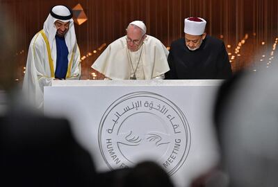 Abu Dhabi's Crown Prince Mohammed bin Zayed al-Nahyan (L) watches as Pope Francis (C) and Egypt's Azhar Grand Imam Sheikh Ahmed al-Tayeb sign documents during the Human Fraternity Meeting at the Founders Memorial in Abu Dhabi on February 4, 2019. Pope Francis rejected "hatred and violence" in the name of God, on the first visit by the head of the Catholic church to the Muslim-majority Arabian Peninsula. / AFP / Vincenzo PINTO                      
