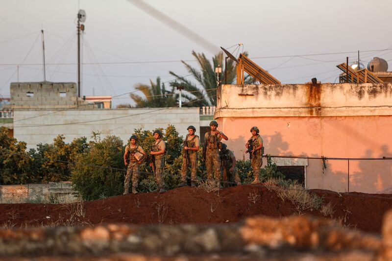 Turkish soldiers guard an army observation point as Syrian demonstrators gather nearby in Ibbin Samaan. AFP