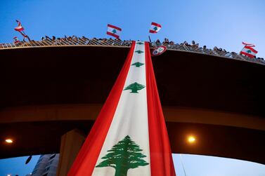 Demonstrators stand on a bridge decorated with a national flag during an anti-government protest along a highway in Jal El Dib, Lebanon on October 21, 2019. Reuters