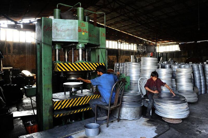 Afghan labourers work a press at an aluminium workshop in Herat.