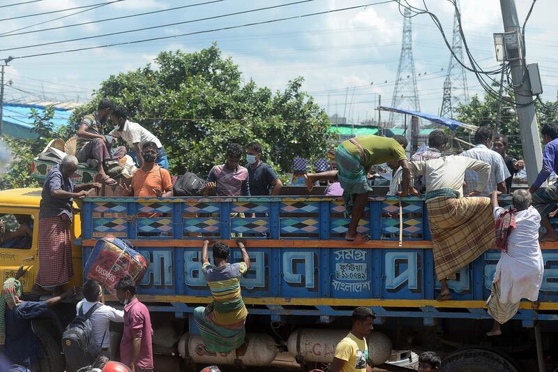 People get on a truck as they travel back to their homes on the eve of the Muslim festival of Eid al-Adha or the festival of sacrifice, in Dhaka on July 31, 2020. Eid al-Adha, feast of the sacrifice, marks the end of the Hajj pilgrimage to Mecca and commemorates Prophet Abraham's readiness to sacrifice his son to show obedience to Allah. / AFP / Munir Uz zaman / Munir Uz zaman
