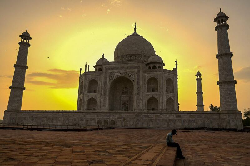 A security guard takes a break as the sun rises behind the Taj Mahal after it reopened to visitors. AFP