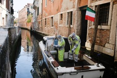 Municipal workers in protective gear sanitise a boat in Venice as they prepare to allow some shops to reopen on April 14. S&P Global estimates lockdowns in european countries will last about eight weeks, on average. Reuters