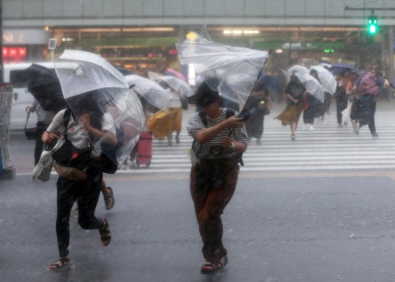 Pedestrians crossing a road struggle against the strong wind and rain in Tokyo, Japan.  EPA / JIJI